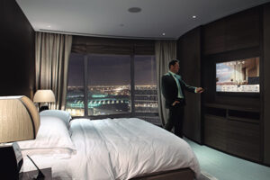 Hombre en habitación de hotel encendiendo la tV con el mando a distancia